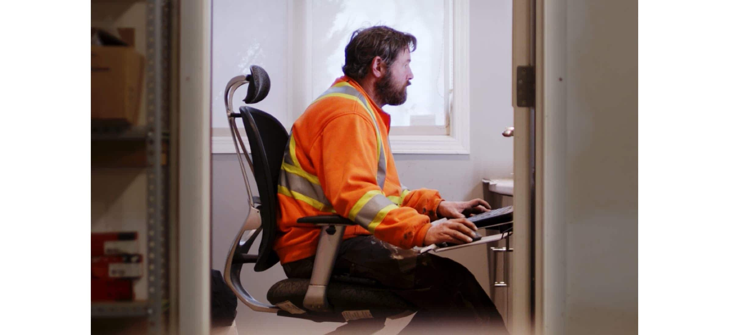 Brad in his high visibility gear sitting at his computer in his office.